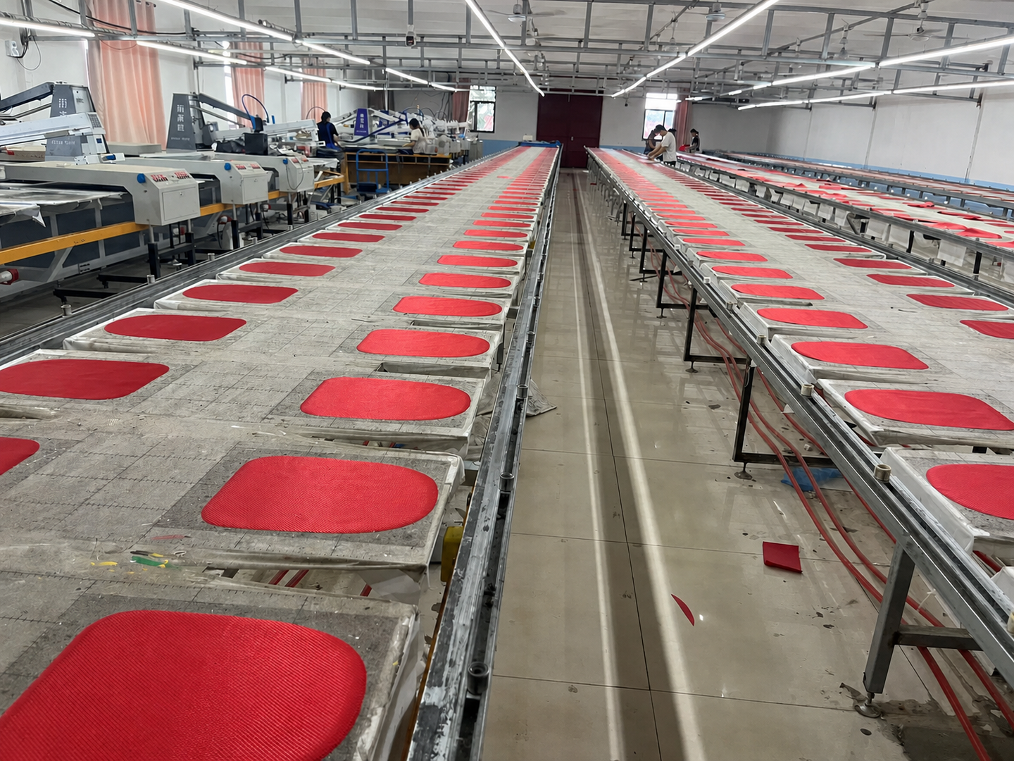 Red bag panels laid out on long tables in a printing work area