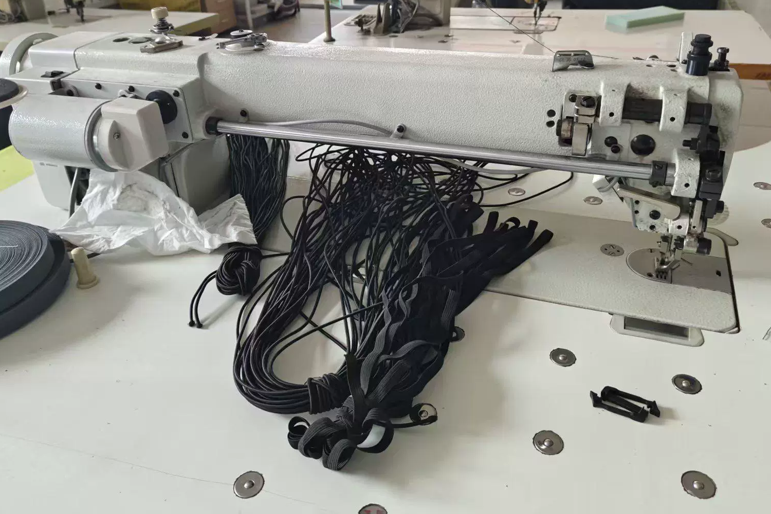 User-supplied photograph of industrial sewing equipment and prepared bag carrying components
